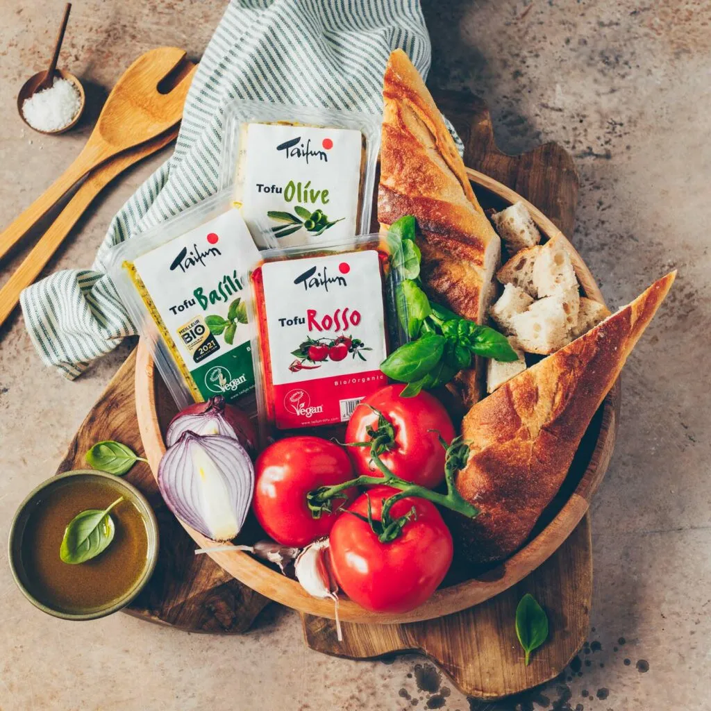 Frischer Panzanella Brotsalat mit gewürfeltem Tofu auf einem Holztisch