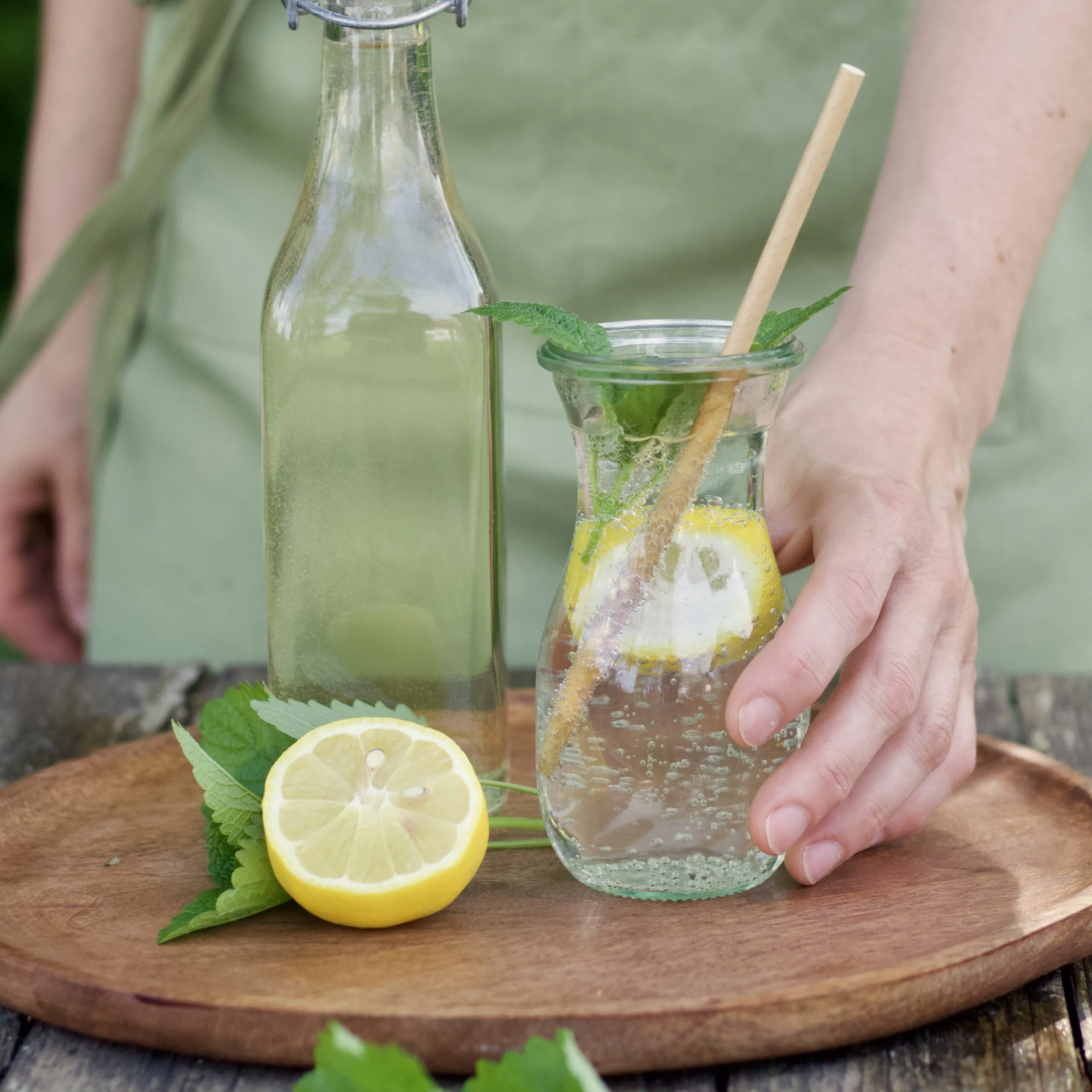 Frischer Zitronenmelissensirup in einer Flasche, umgeben von Zitronenmelisseblättern – ein ideales Getränk für heiße Sommertage.