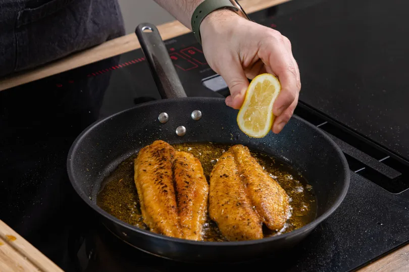 Frischer Zitronensaft über das gebratene Pangasiusfilet träufeln