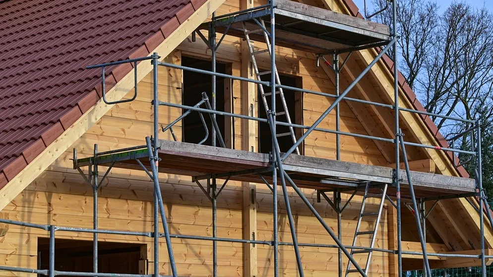 Für Beton gibt es im Bau auch Alternativen. Zum Beispiel Holz oder Ziegel aus Lehm. Im Bild: Baugerüst vor der Fassade eines Holzhauses | Bild: picture-alliance/dpa/Foto: Patrick Pleul