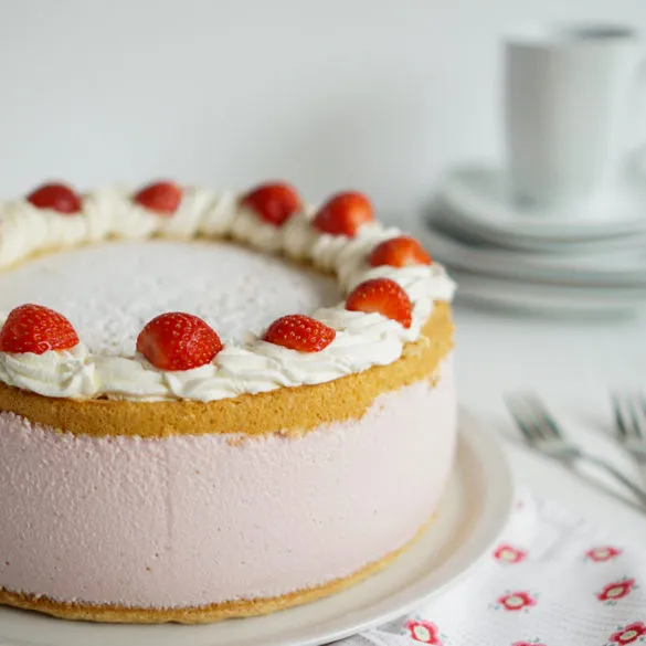 Ganze Erdbeer-Käsesahnetorte von oben mit Sahnetupfen und Puderzucker