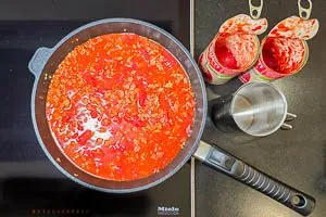 Gebratenes Hackfleisch mit Tomatensoße ablöschen