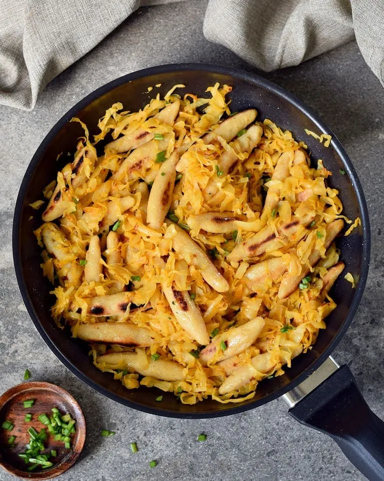 Gebratenes Sauerkraut mit veganen Schupfnudeln in einer Pfanne angerichtet
