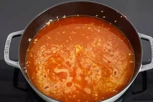 Geflügelfond und Safranfäden werden zum Paella Reis gegeben