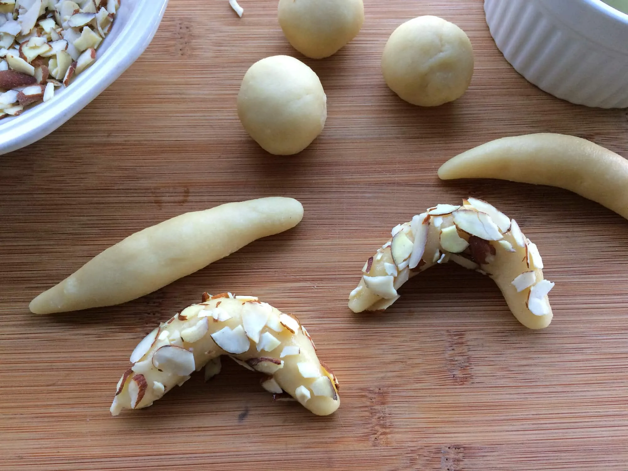 Geformte Mandelhörnchen, mit Mandelsplittern bedeckt und auf einem Backblech arrangiert