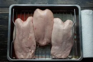 Gefrorene Gänsebrust wird langsam im Bräter im Kühlschrank aufgetaut