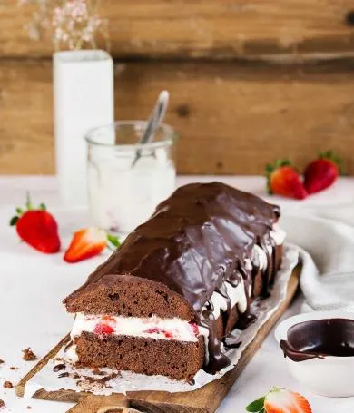 Gefüllter Schoko-Erdbeerkuchen mit cremiger Sahne und frischen Erdbeeren, dekoriert mit Schokoladensauce.