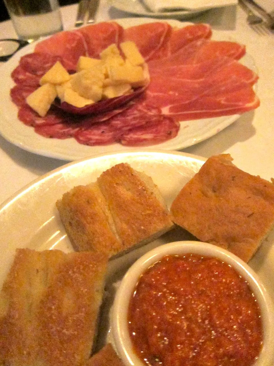 Gefüllter Tisch mit kostenlosen Köstlichkeiten im Primola: Süchtig machende Grissini, Salami, Focaccia…