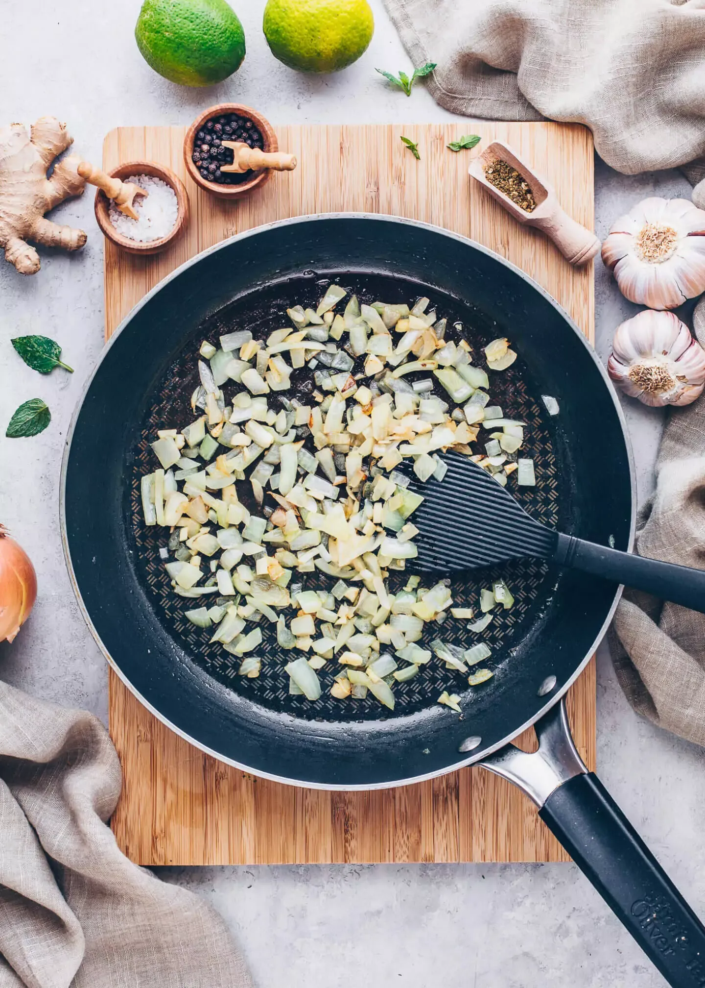 Gehackte Zwiebeln werden in Kokosöl in einer Pfanne für den veganen Linsen-Dal angeschwitzt.