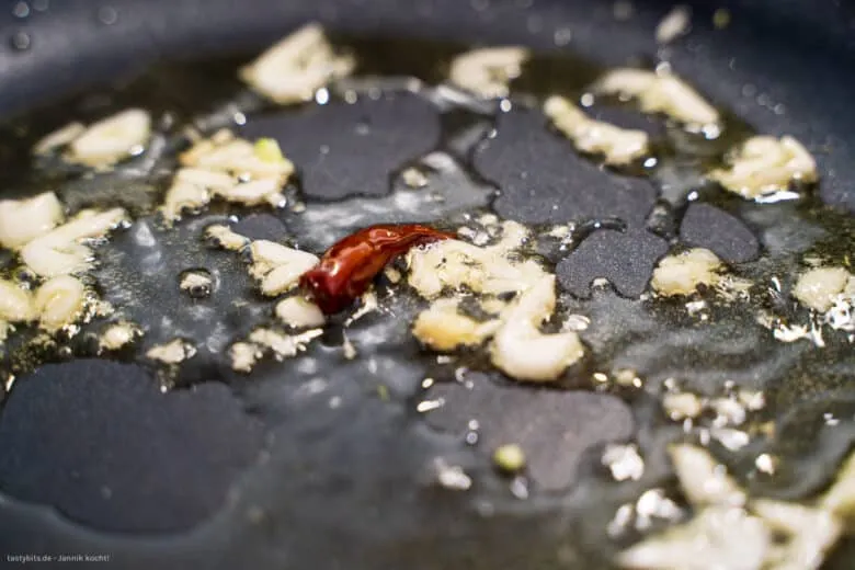 Gehackter Knoblauch und getrocknete Chilischote in Olivenöl anbraten