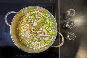 Gemüse und Gewürze in die Brühe geben.