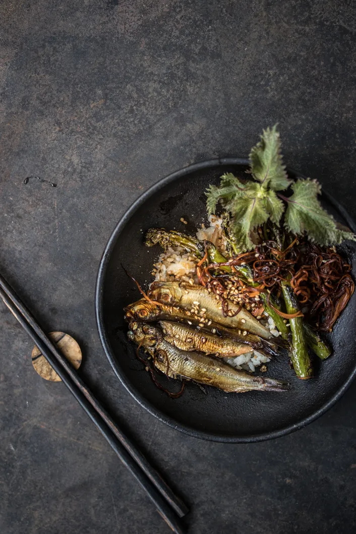 Geräucherte Kieler Sprotten auf Dashi-Reis mit Brokkoli und Karotten, japanisch inspiriert, serviert in einer eleganten Schale