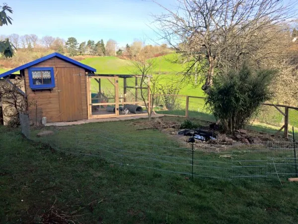 Geräumiges Kaninchengehege mit integriertem Gartenhaus als Schutzhütte, das eine artgerechte Haltung von Hasen im Garten ermöglicht