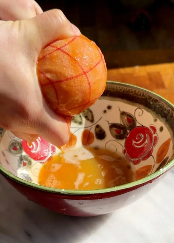 Geriebene Kartoffeln, Karotten und Zucchini werden in einem Küchentuch ausgedrückt, um Feuchtigkeit zu entfernen