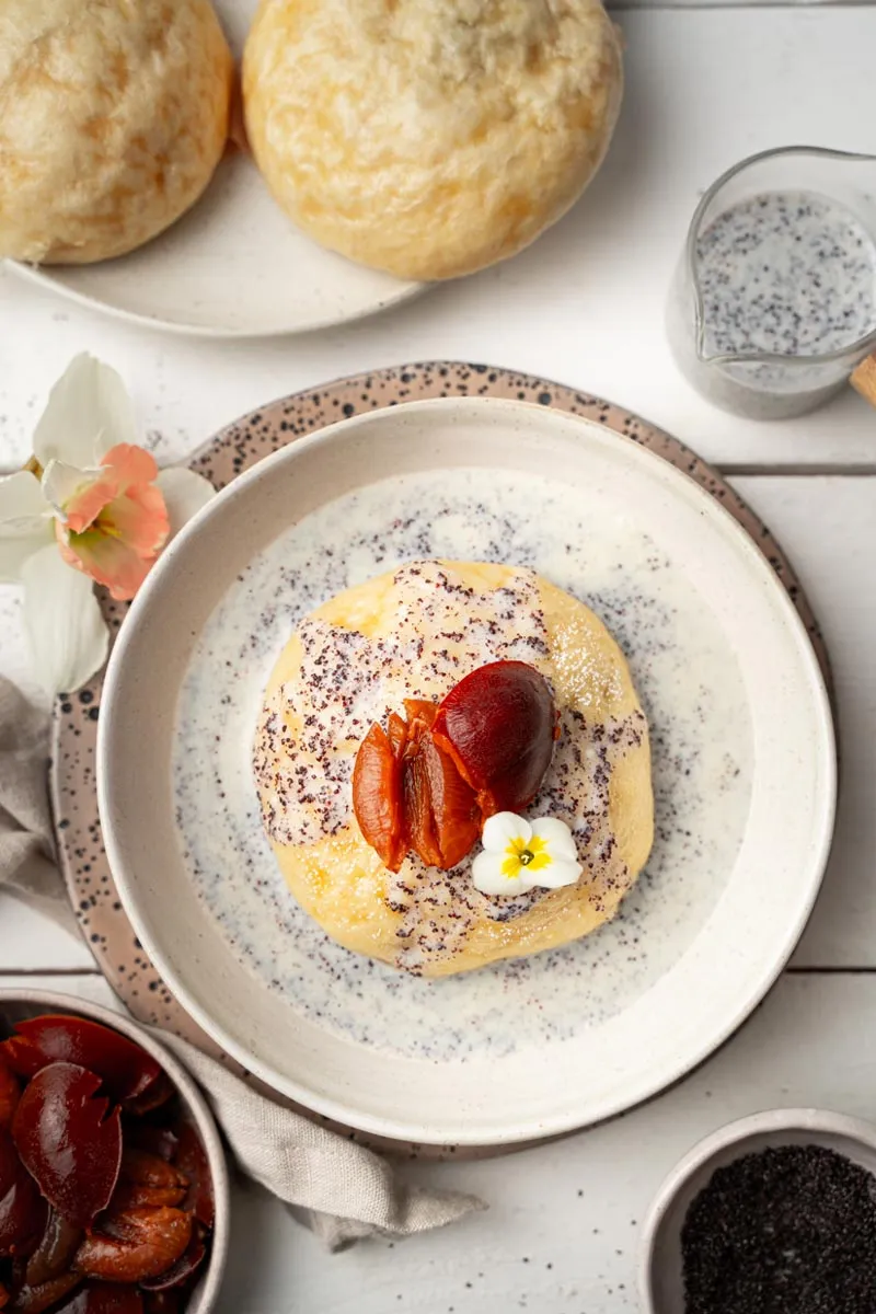 Germknödel mit leuchtender Pflaumenfüllung und cremiger Vanille-Mohn-Soße, perfekt gedämpft und bereit zum Servieren.