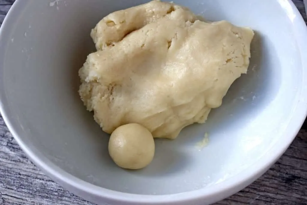 Gerollte Marzipankartoffel-Rohlinge auf einem Backpapier, bereit zum Bestäuben mit Kakao