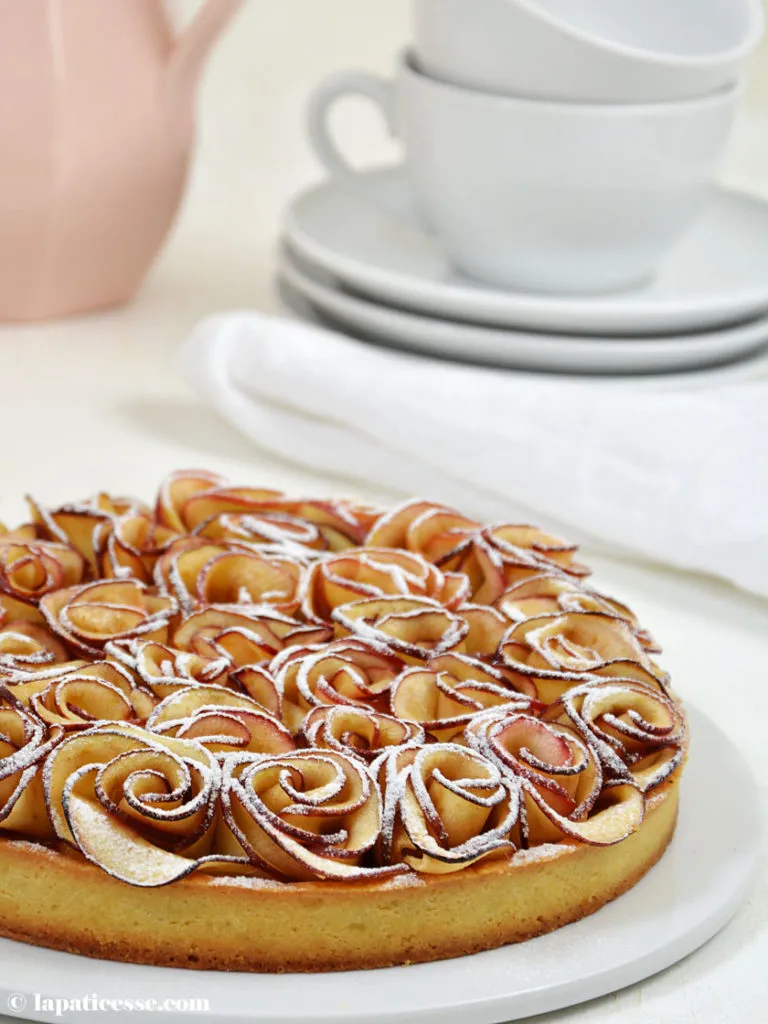 Gesamtaufnahme der fertigen Apfelrosen-Tarte, bestäubt mit Puderzucker – ein beeindruckendes Patisserie-Rezept, geeignet für Promibacken.