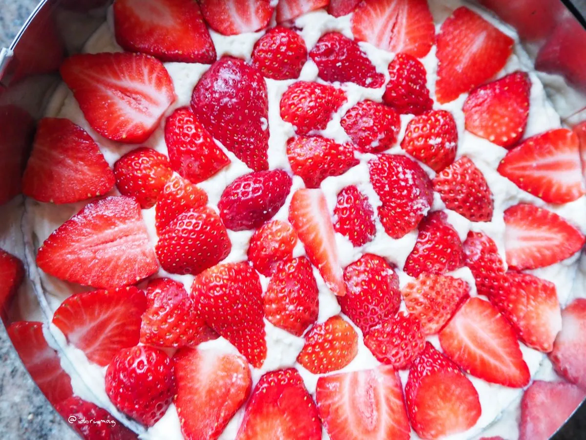 Geschlagene vegane Sahne auf der Erdbeermarmeladenschicht des Biskuitkuchens