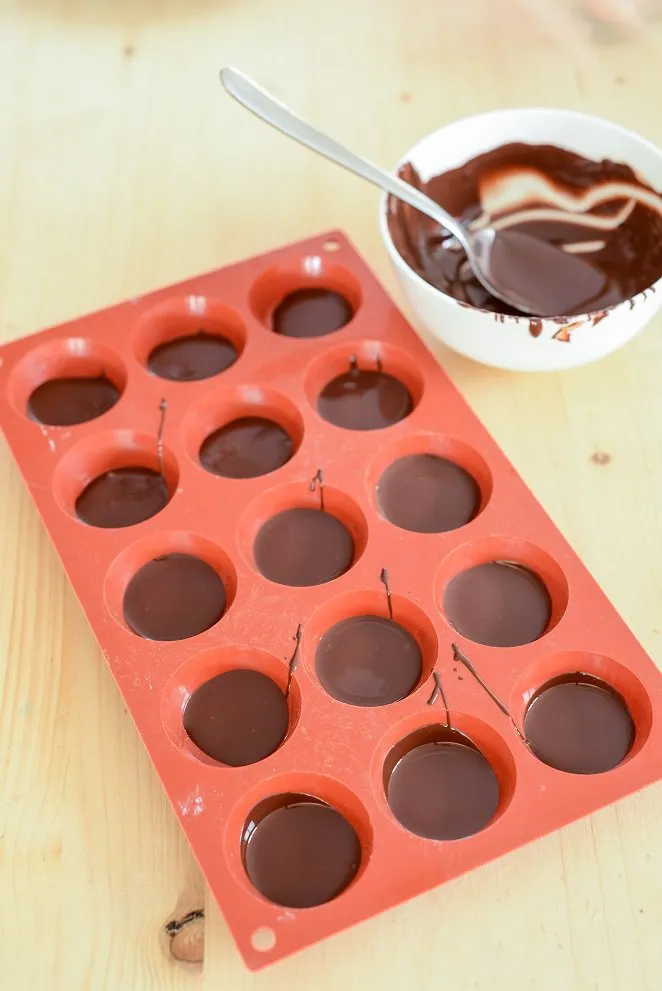 Geschmolzene Schokolade in kleinen Backförmchen als Basis für die Florentiner.