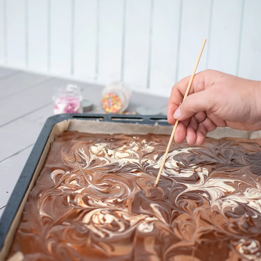 Geschmolzene Schokoladenstücke auf dem Backblech nach dem Ofen, die Oberfläche ist glänzend und bereit zum Verzieren für die selbstgemachte Bruchschokolade.