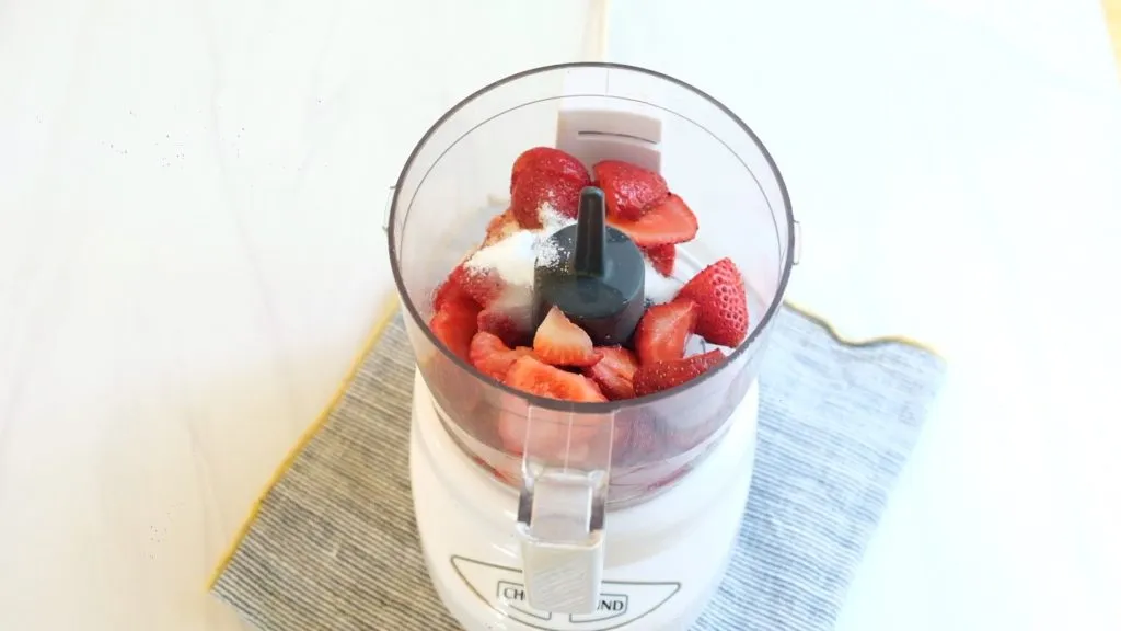 Geschnittene Erdbeeren, Orangensaft und Zucker in einem Mixer