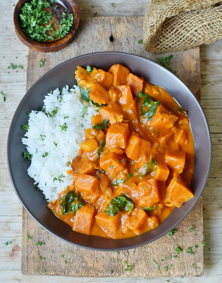gesundes Süßkartoffel-Kokos-Curry mit Spinat und Reis in einer Schüssel, von oben gesehen