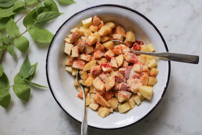 Gewürfelte Kartoffeln mit Kräutern und Semmelbröseln, bereit für das Rösten im Ofen.