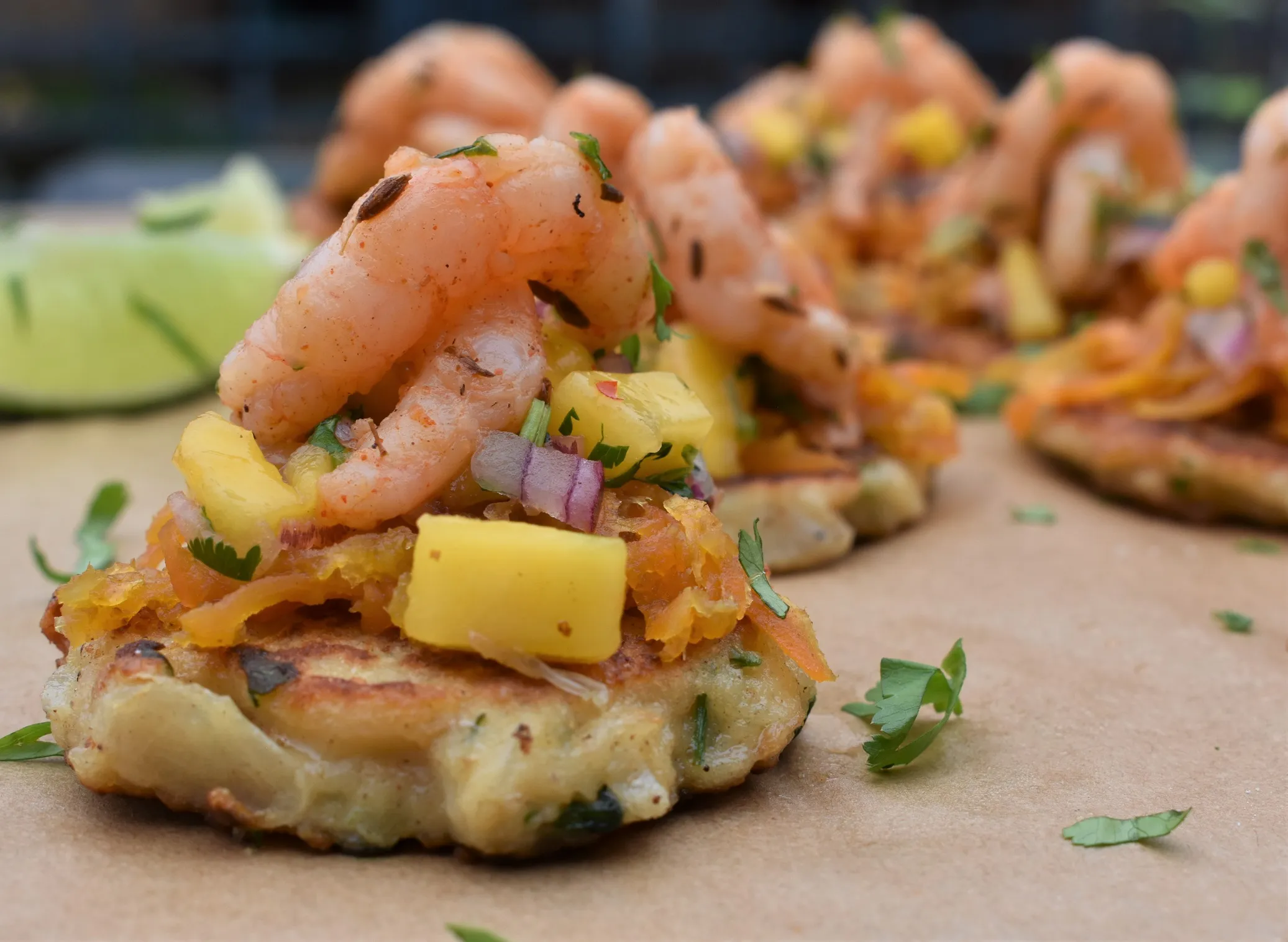 Gewürzte Kaspressknödel belegt mit Garnelen, Kreuzkümmel, frischer Mango und Limette.