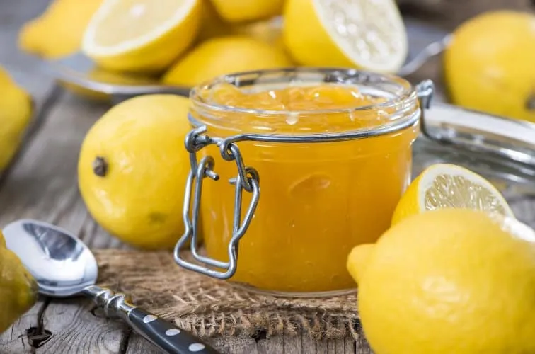 Glas italienische Zitronenmarmelade mit Löffel und frischen Zitronen