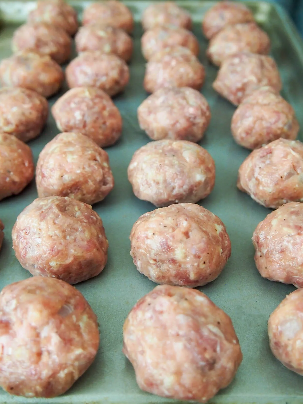 Gleichmäßig geformte schwedische Fleischbällchen auf einem Backblech, bereit zum Braten