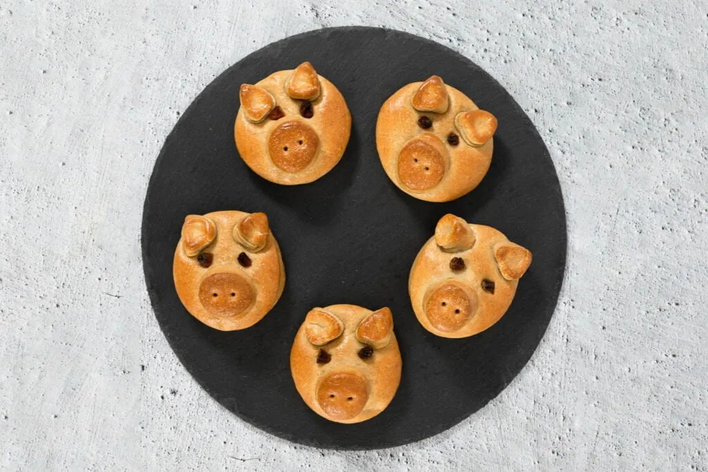 Glücksschweinchen aus veganem Hefeteig auf einer Servierplatte, bereit für Silvester.