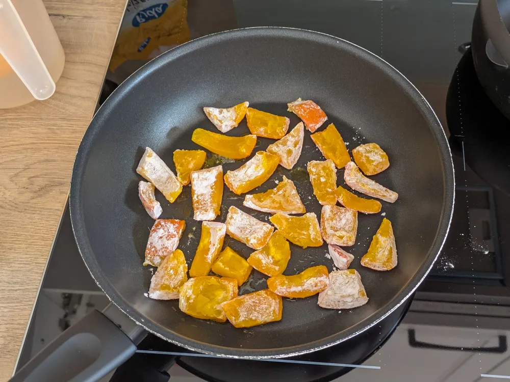 Goldbraun angebratene Kürbisstücke in einer Pfanne für die Zubereitung von Kabocha Nanban.