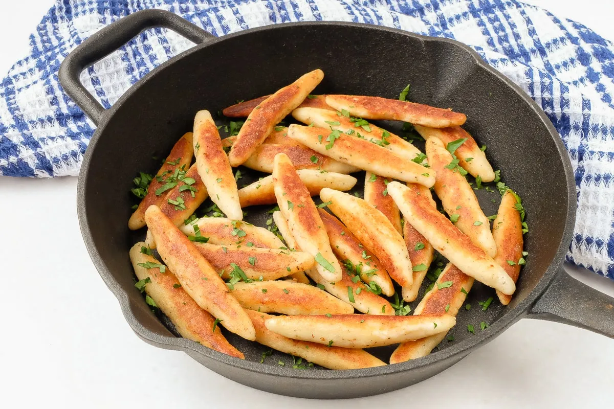 Goldbraun angebratene Schupfnudeln mit frischer Petersilie in einer Pfanne, ein klassisches Rezept.