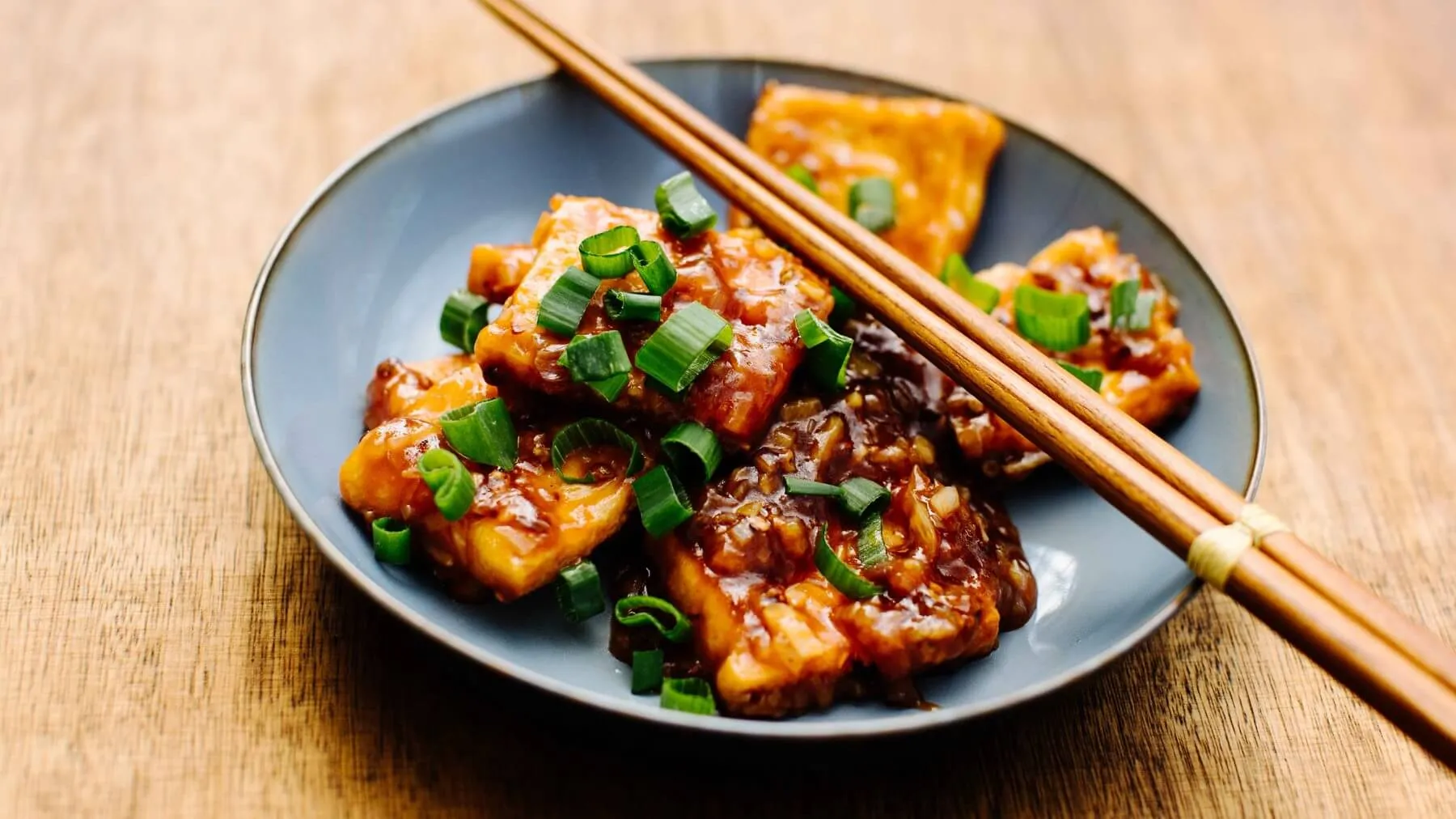 Goldbraun frittierter Tofu, serviert mit einer glänzenden Austernsauce und frischen Frühlingszwiebeln, ein vegetarisches chinesisches Rezept