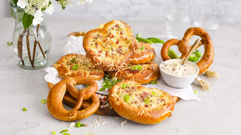 Goldbraun gebackene Flammkuchen-Brezeln mit Speck und Zwiebeln, ideal als schneller Snack oder leichtes Abendessen.