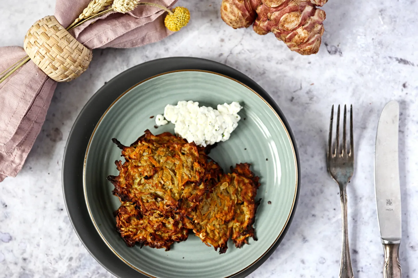 Goldbraun gebackene Topinambur Röstis auf einem Backblech, knusprig und duftend direkt aus dem Ofen.