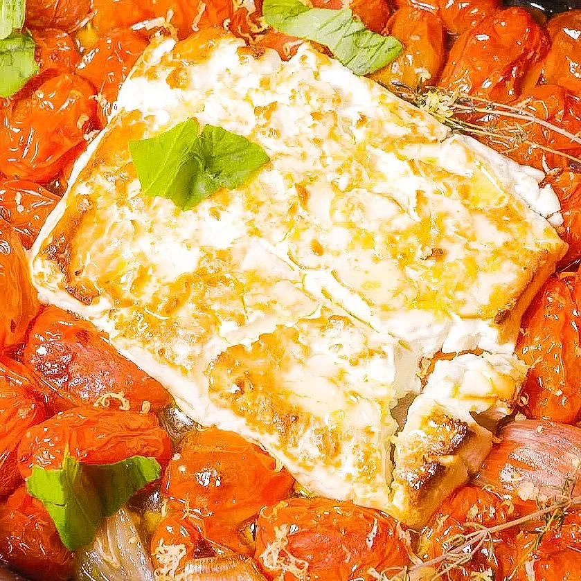 Goldbraun gebackener Schafskäse und saftige, geplatzte Kirschtomaten sprudelnd in der Auflaufform nach dem Ofen, Basis für eine köstliche One Pot Pasta.