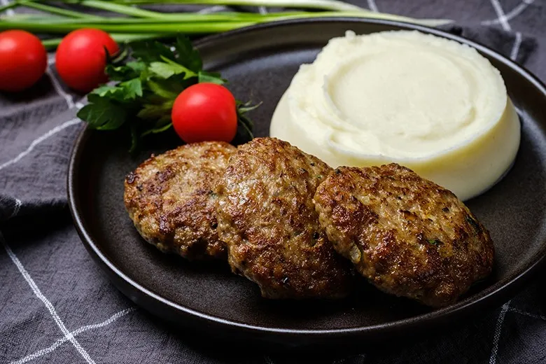 Goldbraun gebratene Frikadellen, auch als Faschierte Laibchen bekannt, mit frischer Petersilie garniert.