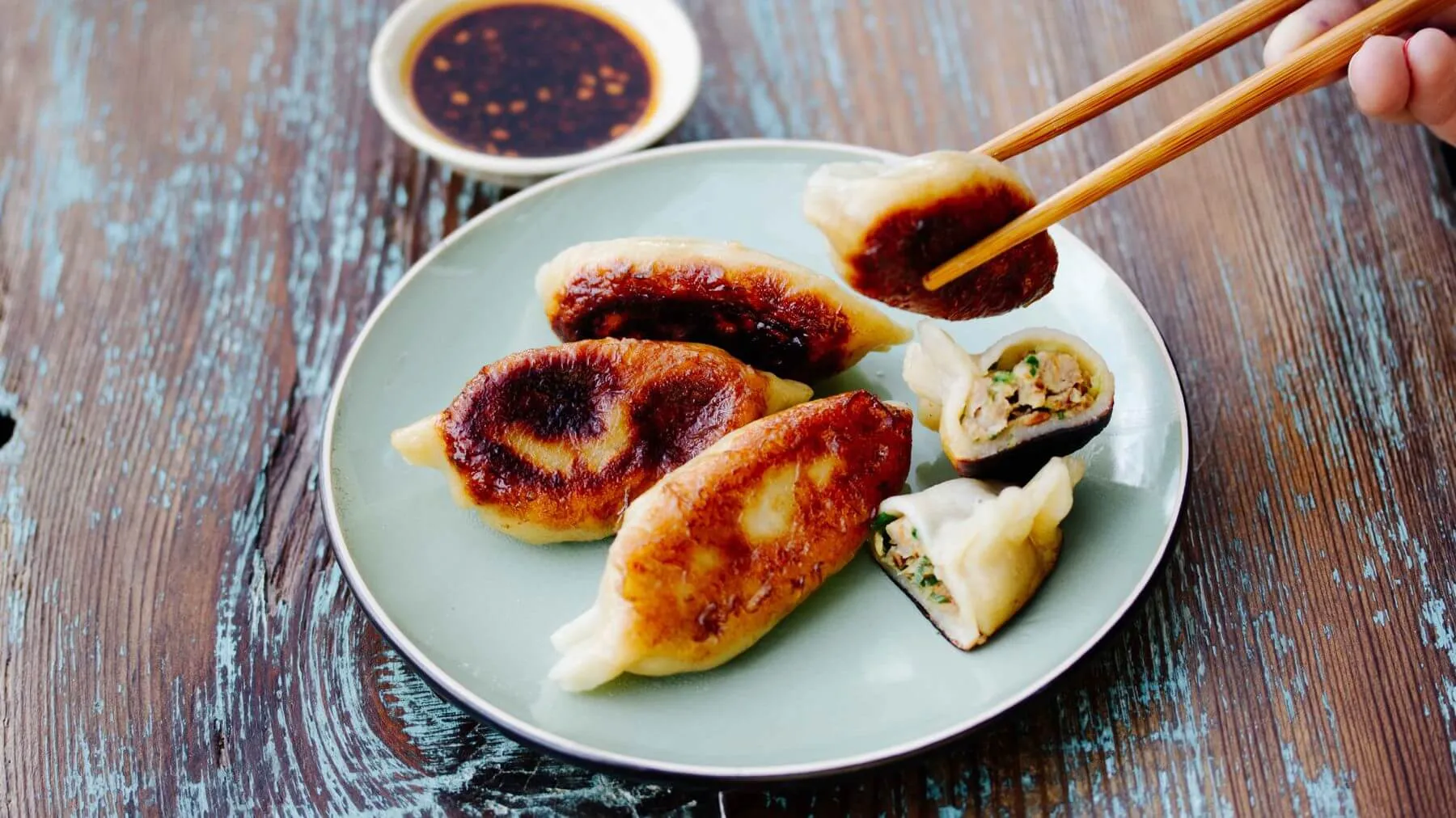 Goldbraun gebratene Jiaozi, auch Potsticker genannt, auf einem Teller angerichtet mit Dip-Sauce, beliebte chinesische Teigtaschen