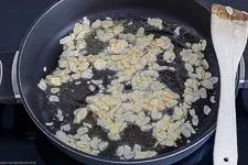 Goldbraun geröstete Mandeln in einer Pfanne, ein wichtiger Bestandteil der cremigen Spinatsauce für den Lachs Spinat Auflauf.