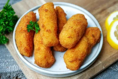 Goldbraune, knusprige Kroketten frisch auf einem weißen Teller serviert