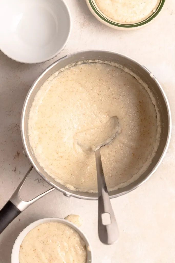 Grießbrei in einer Servierschale, angerichtet mit frischen Himbeeren und Zimtzucker.