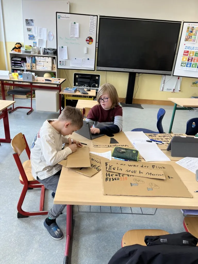 Grundschüler demonstrieren mit selbstgemalten Plakaten für eine saubere Umwelt, begleitet von der Polizei.