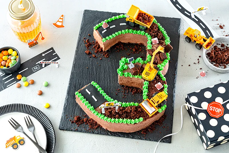 Grüne Sahnetupfer als kreative Dekoration am Rand des Baggerkuchens