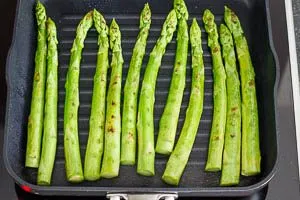 Grüne Spargelstangen werden in einer großen Pfanne mit etwas Olivenöl goldbraun und knackig gebraten.