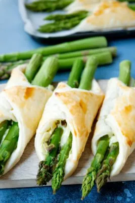 Grüner Spargel umwickelt mit Blätterteig auf einem Backblech