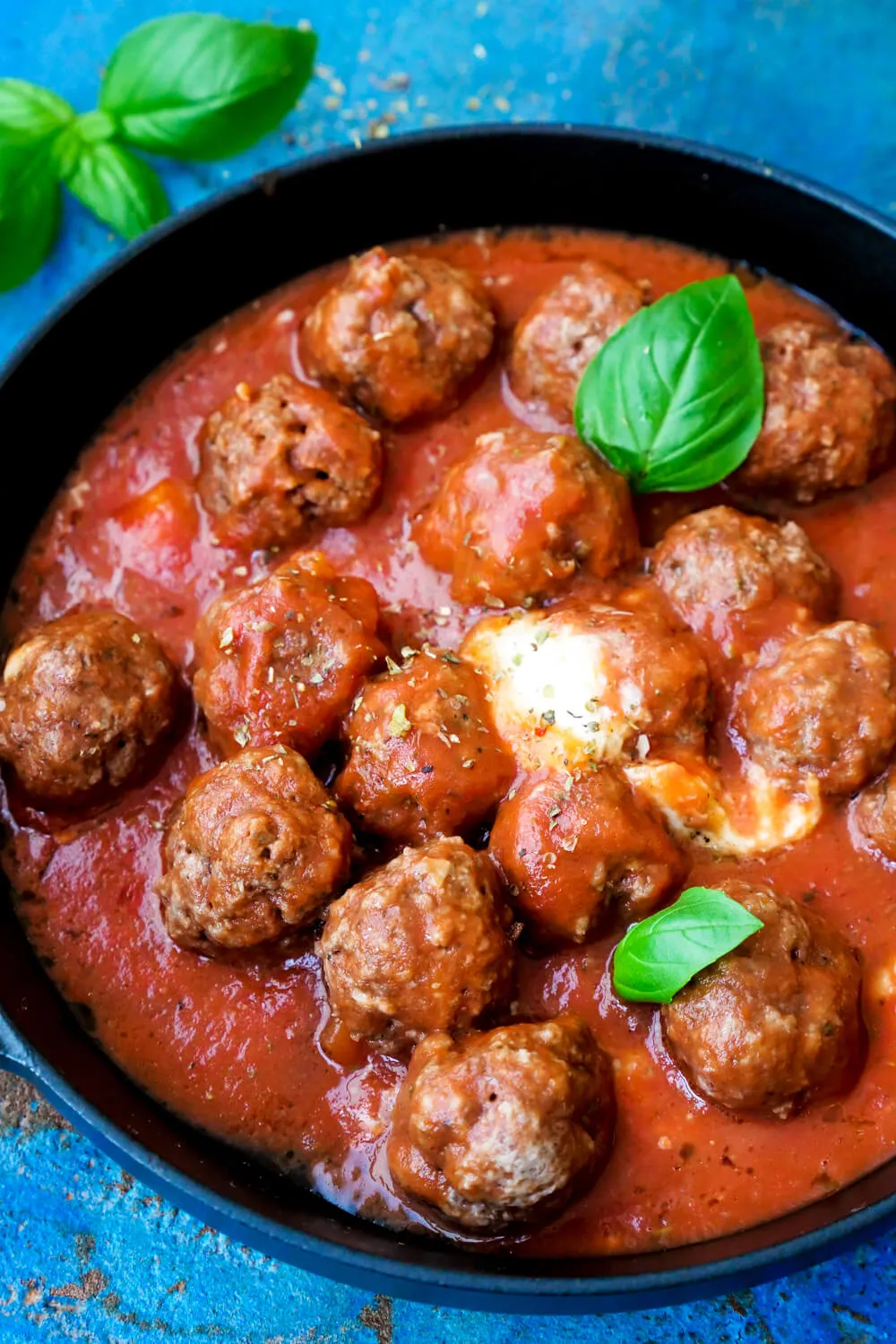 Hackbällchen in Tomatensauce mit Mozzarella überbacken. Alternative Text: Hackbällchen in Tomatensauce, mit frischem Basilikum und geschmolzenem Mozzarella überbacken, serviert als schmackhaftes und gesundes Mittagessen.