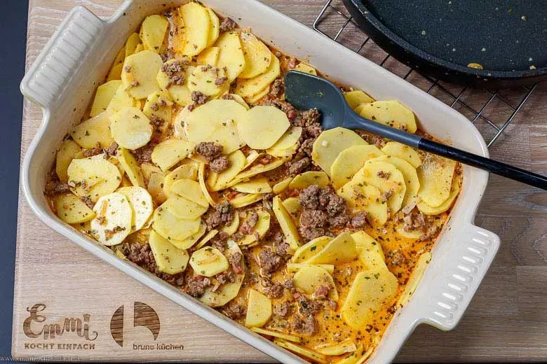 Hackfleischsoße wird über die rohen Kartoffelscheiben in der Auflaufform gegossen