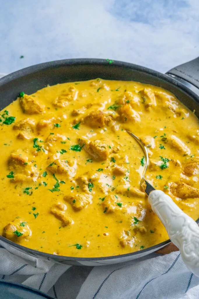 Hähnchen-Curry-Geschnetzeltes in einer Pfanne, vor dem Servieren mit Petersilie garniert