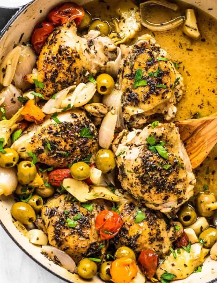 Hähnchen Provencal in einem Schmortopf mit einem Holzlöffel.